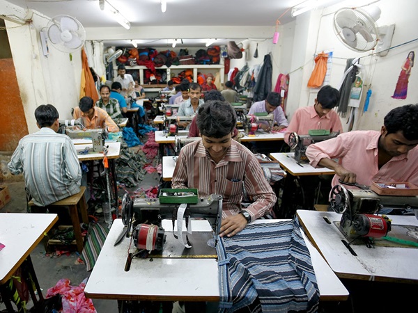 Aziatische mannen in kleine ruimte achter de naaimachines aan het werk