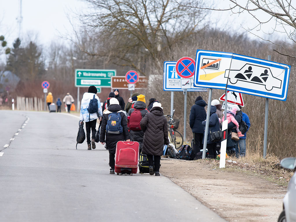 Vluchtende Oekraïners, te voet met koffers, aan de grens met Hongarije