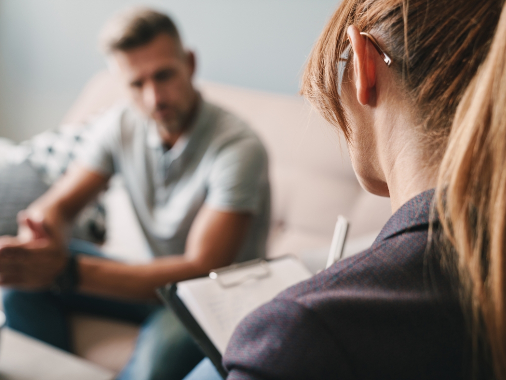 Jonge vrouw in gesprek met jonge man, zij is van achter gefotografeerd, de jonge man is niet herkenbaar.