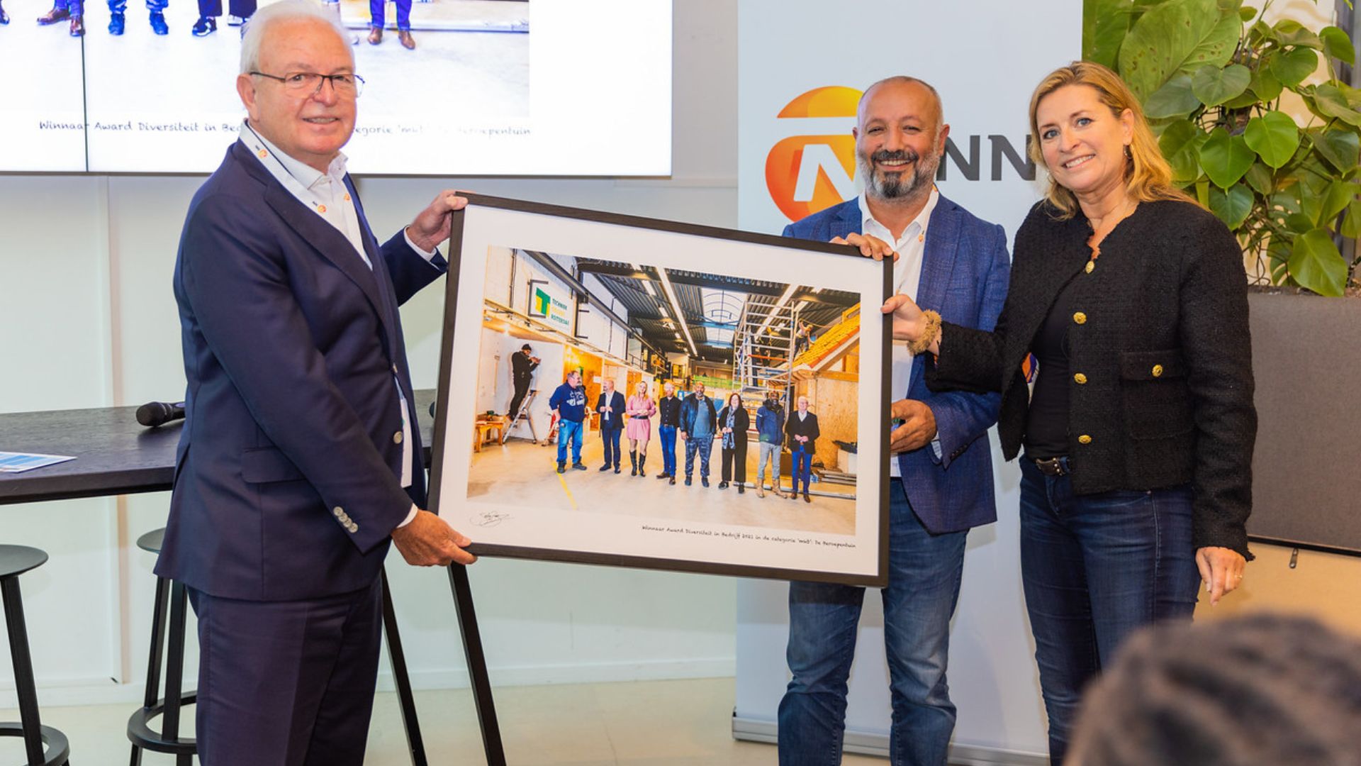 Sacha de Boer (R) overhandigt de Award Diversiteit in Bedrijf 2021, categorie ‘midden- en kleinbedrijf’ uit aan Henk van der Beek (L) en Seyit Yeyden (M) van De Beroepentuin (MKB Rotterdam-Rijnmond)
