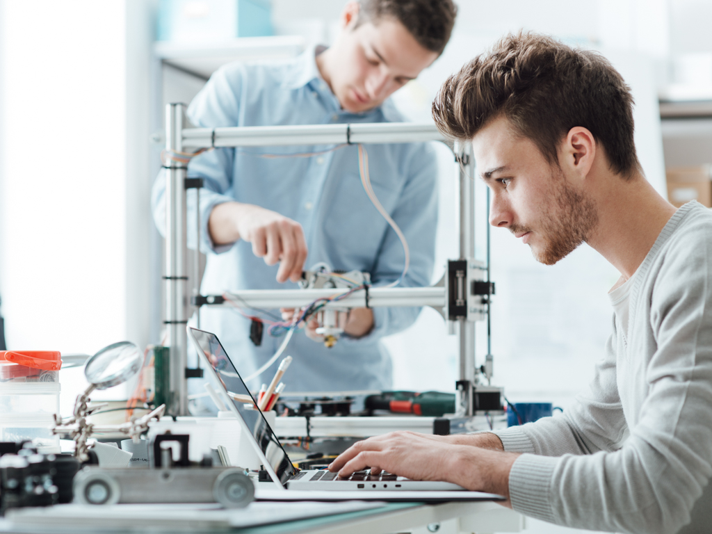 Techniekstudenten passen de componenten van een 3D-printer aan.