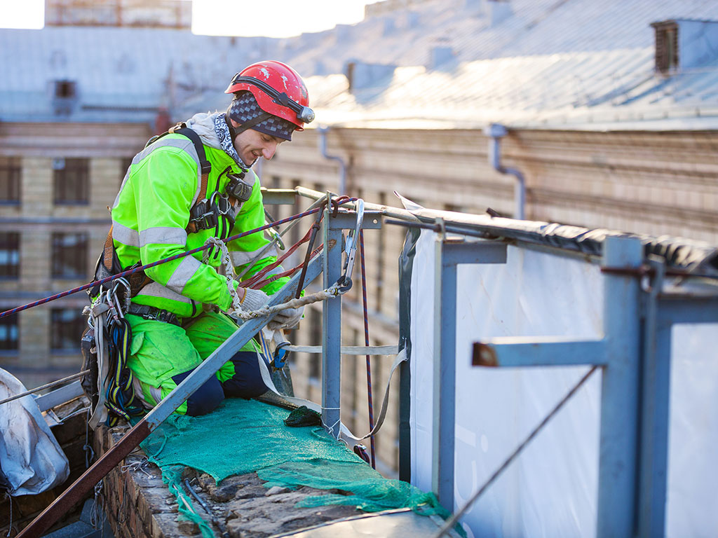 Man op dak in veiligheidskleding en aangelijnd aan het werk