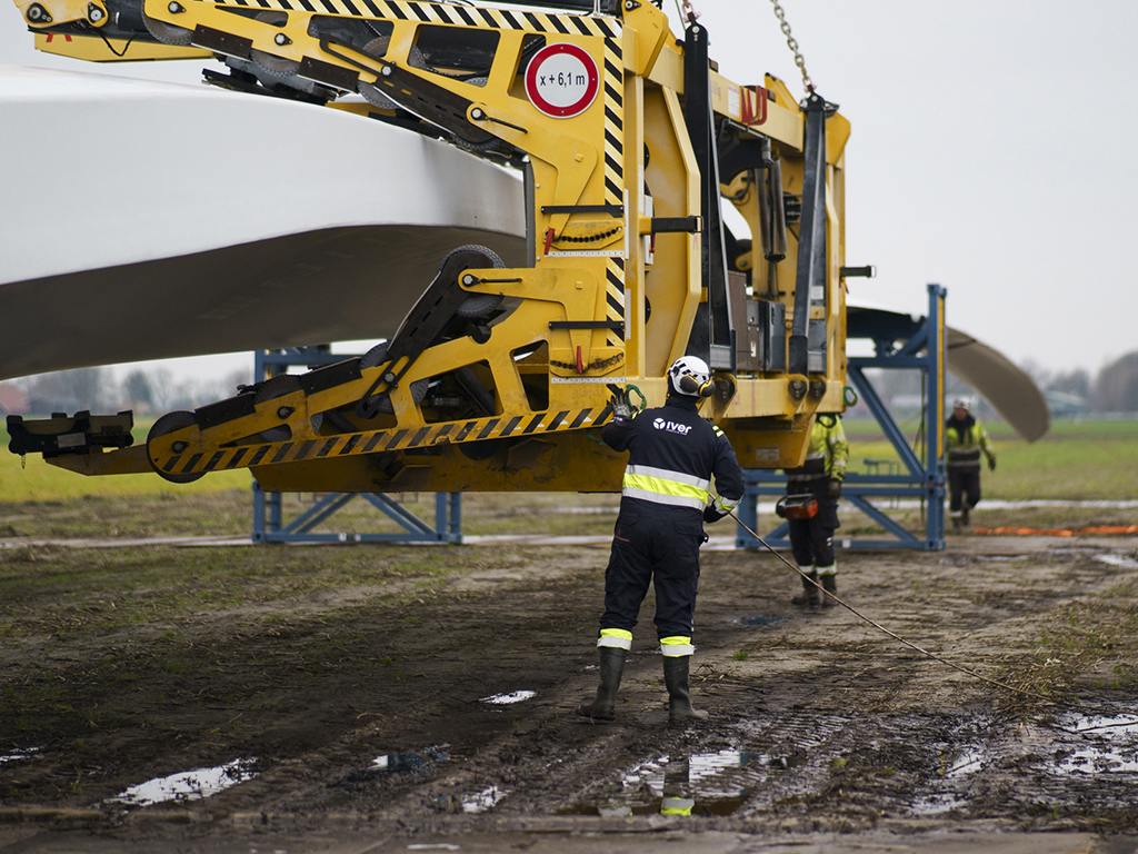 Mannen in werkkleding bij een grote machine in een weiland (van het bedrijf Iver)