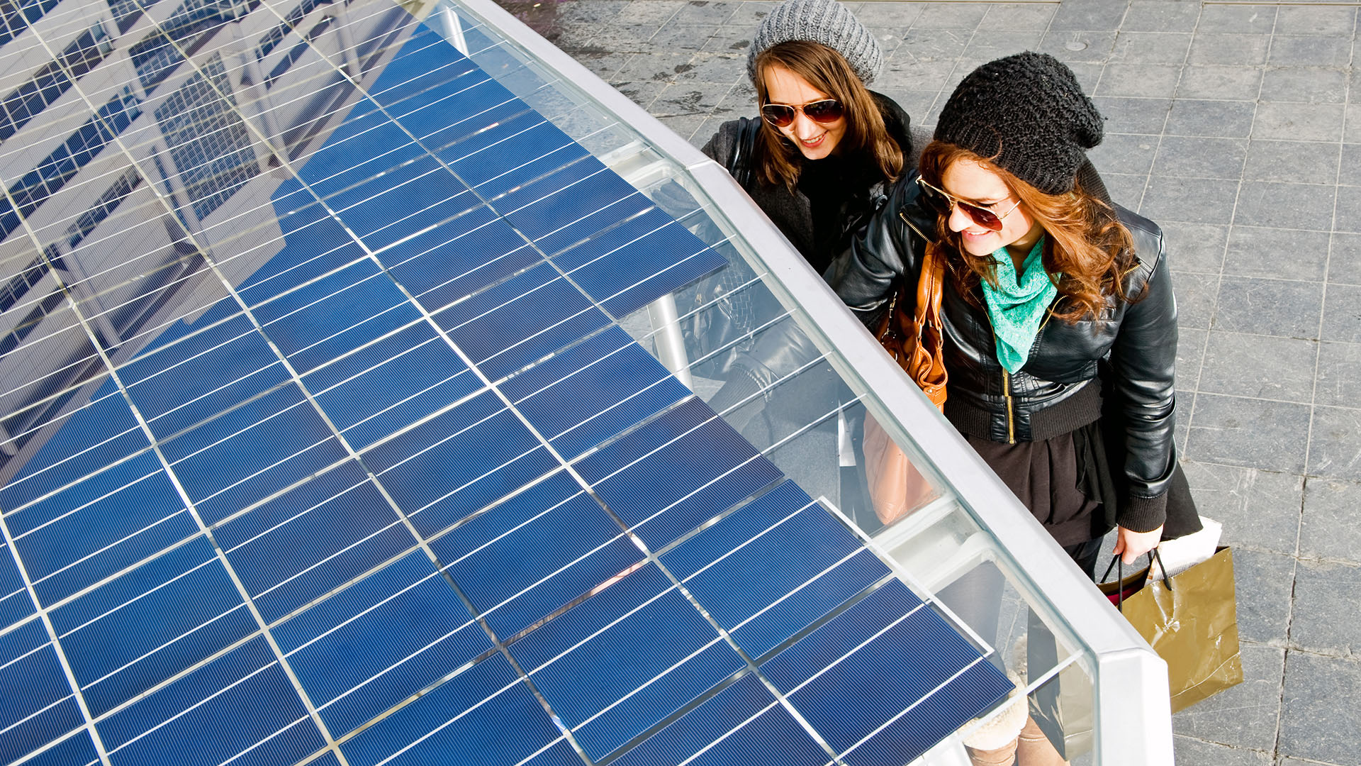 Twee jonge vrouwen staan naast een tuc tuc op zonne-energie