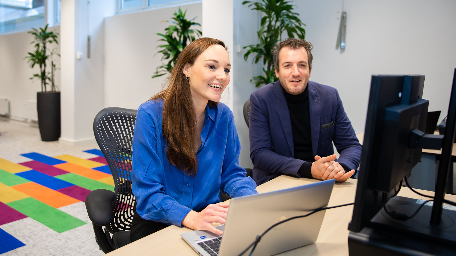 Twee medewerkers aan de laptop in kantoorruimte