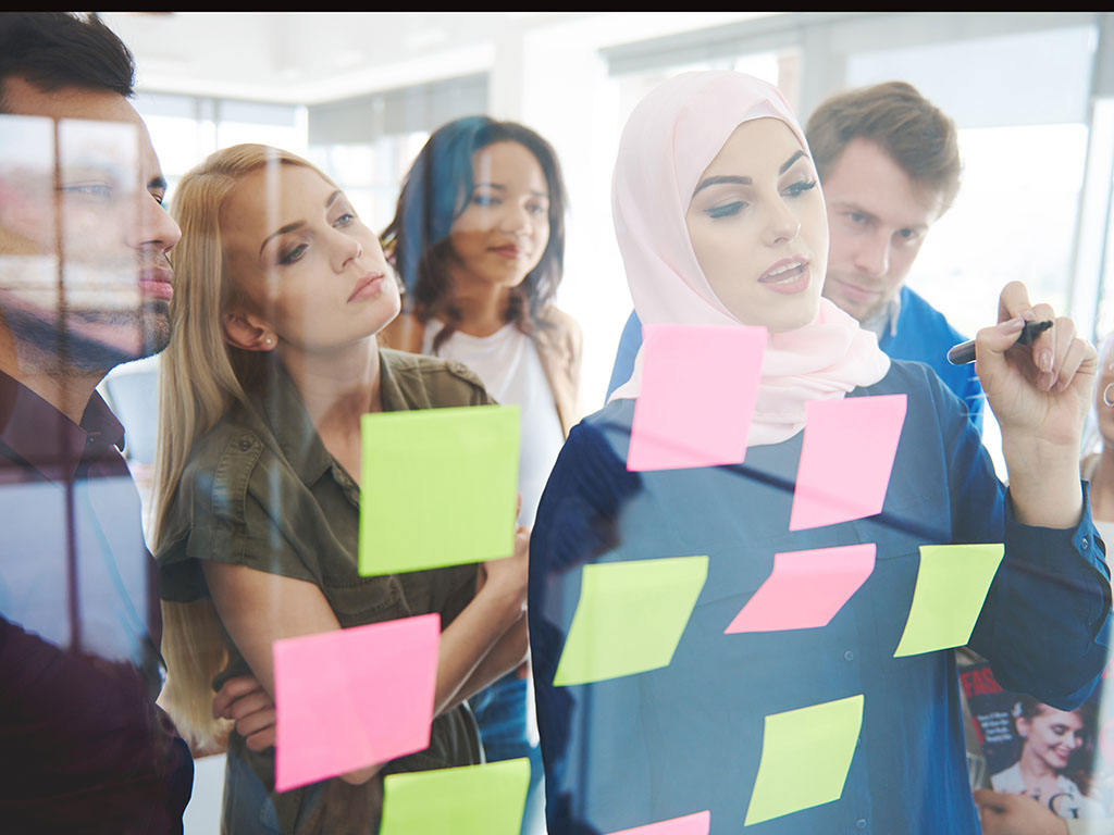 Jonge vrouw met hoofddoek voor een glazen wand met post-it's