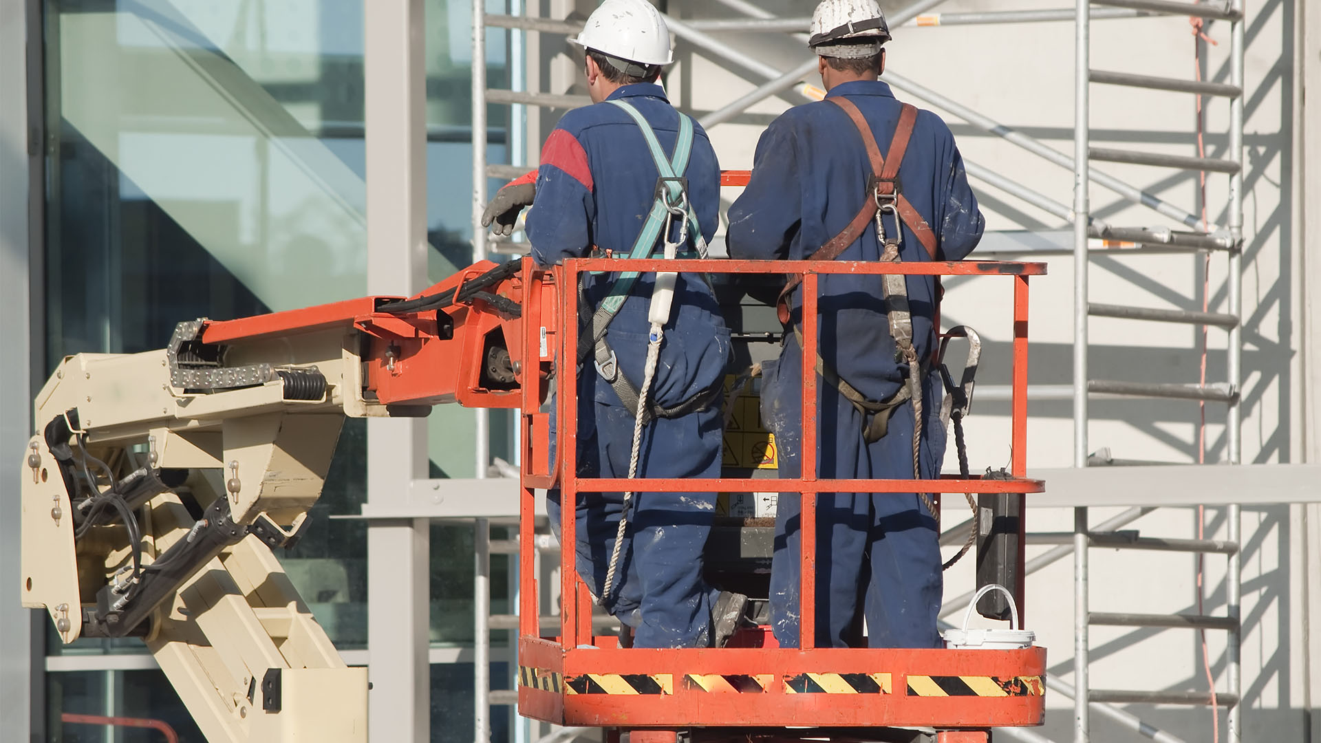 Werknemers dragen veiligheidsharnassen op een hoogwerker