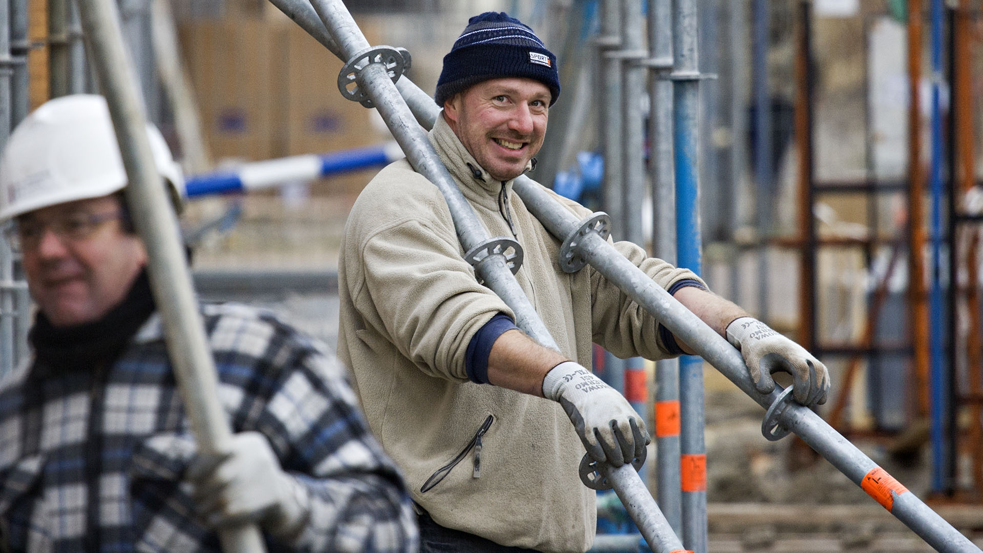 Mannen werkzaam in de bouw met steigermateriaal in winterkleding