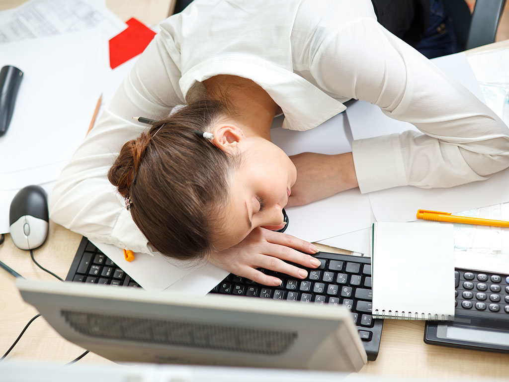 Vermoeide vrouw aan bureau met laptop
